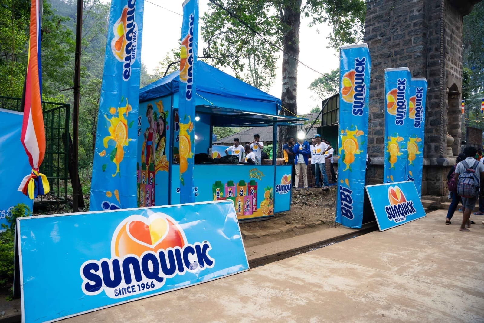 Sunquick branded feather flags and printed boards at an event activation stall