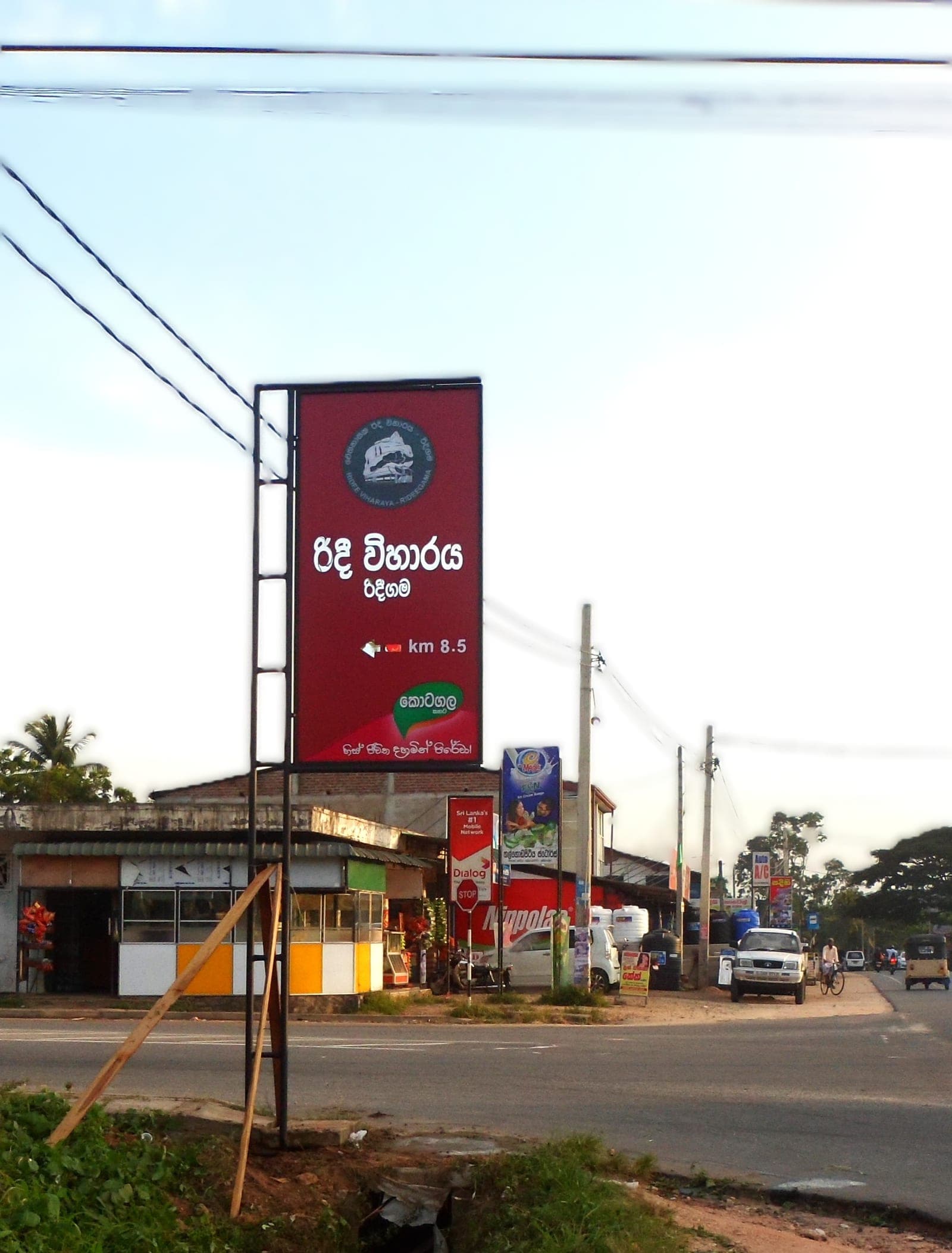 Pole-mounted circular dealer board beside a roadside shop