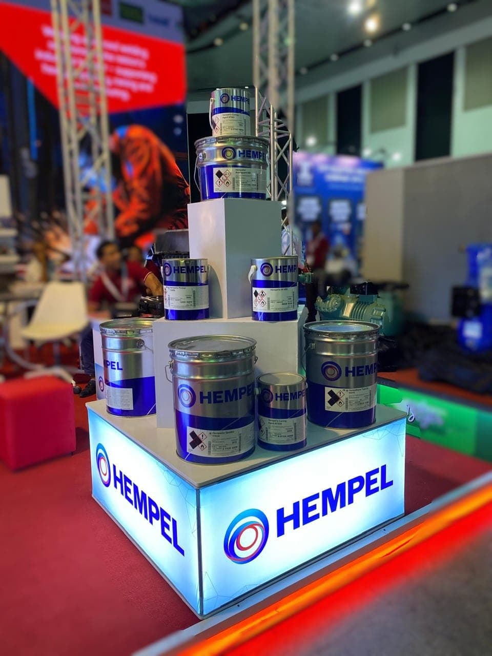 Hempel paint product display stand with tins and a lit base
