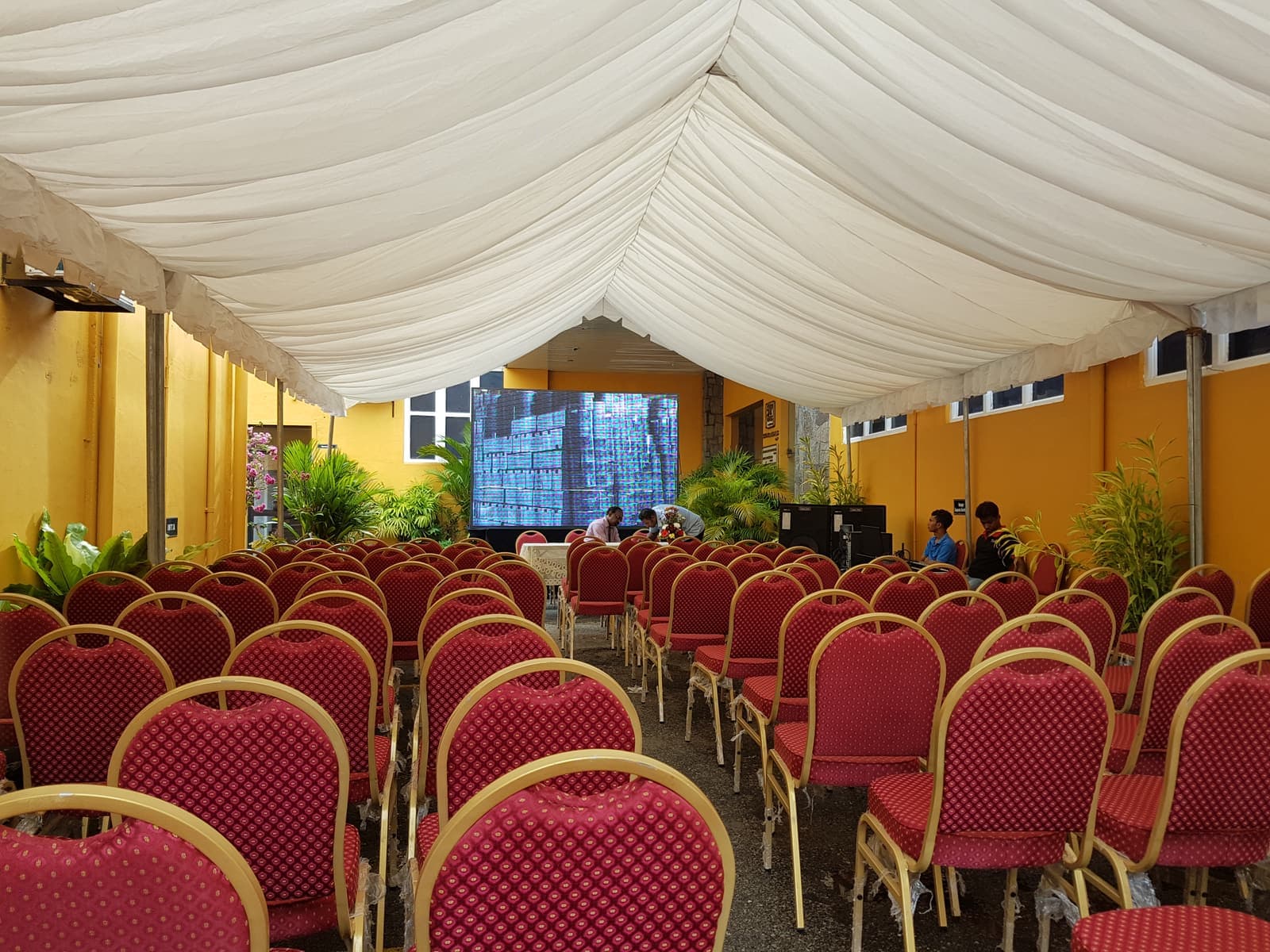 Marquee event hall set with rows of red chairs facing the stage