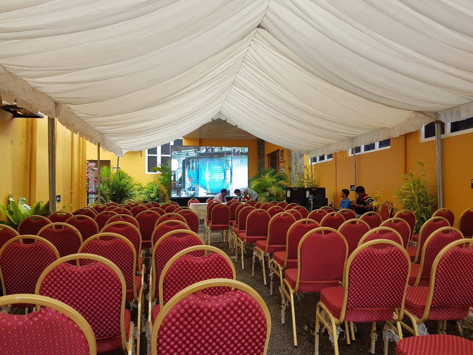 Banquet marquee with red event seating and a stage screen
