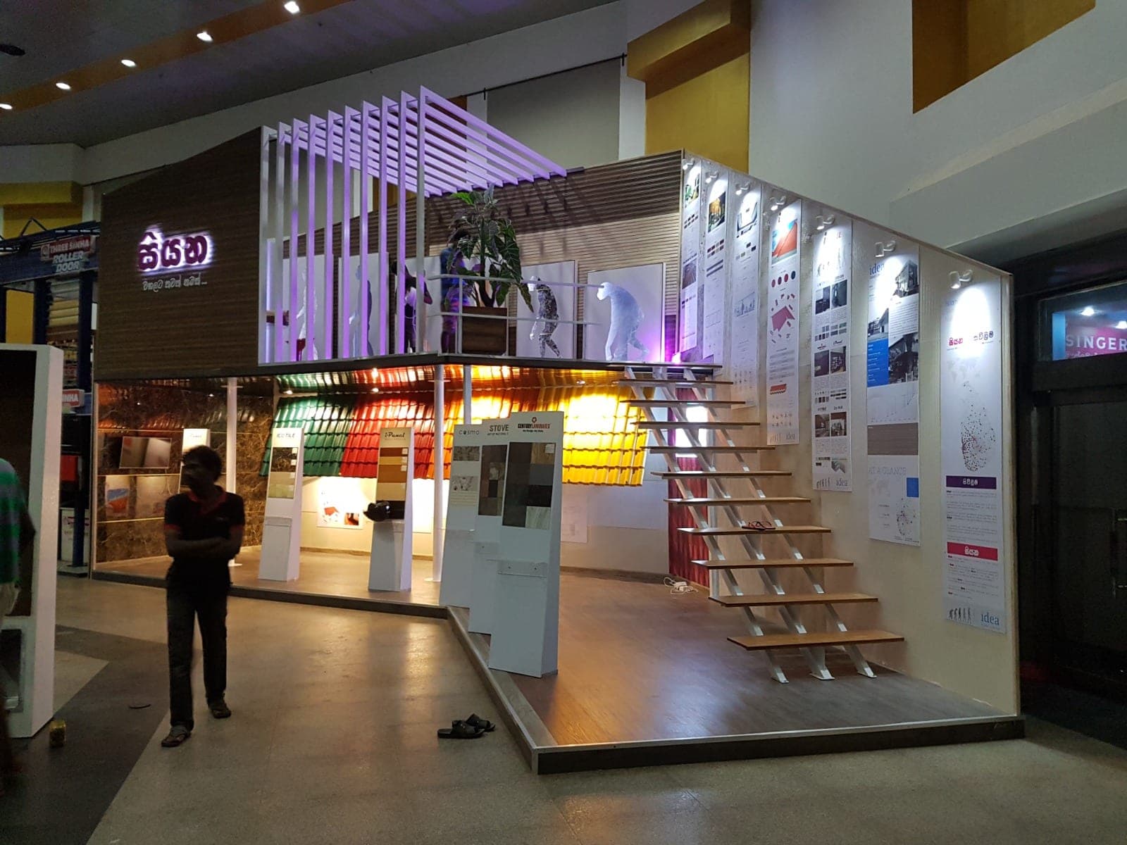 Colourful backlit exhibition stand with a timber staircase and lit shelving