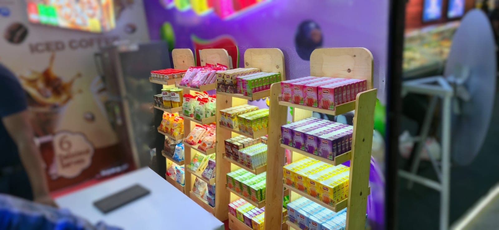 Product shelving inside the Delish stall under purple cove lighting