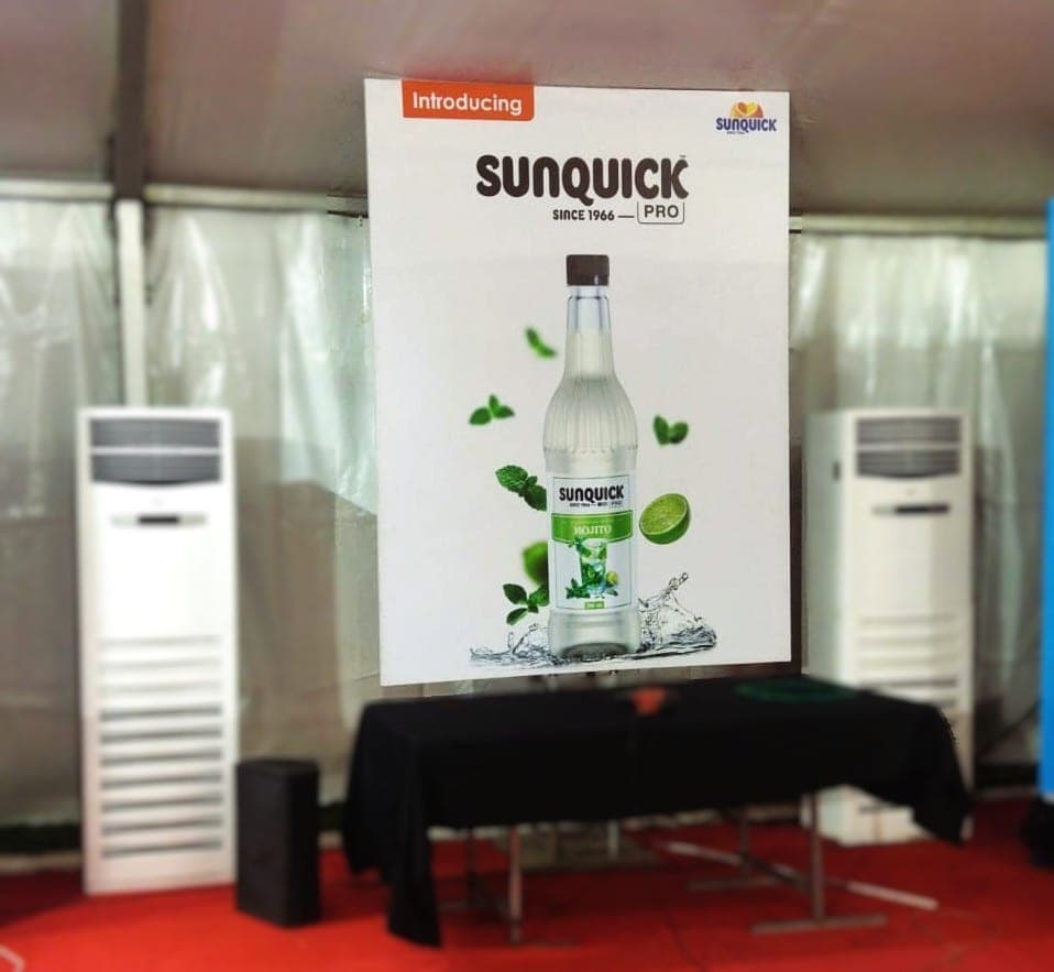 Sunquick PRO launch backdrop with a product bottle graphic and skirted table