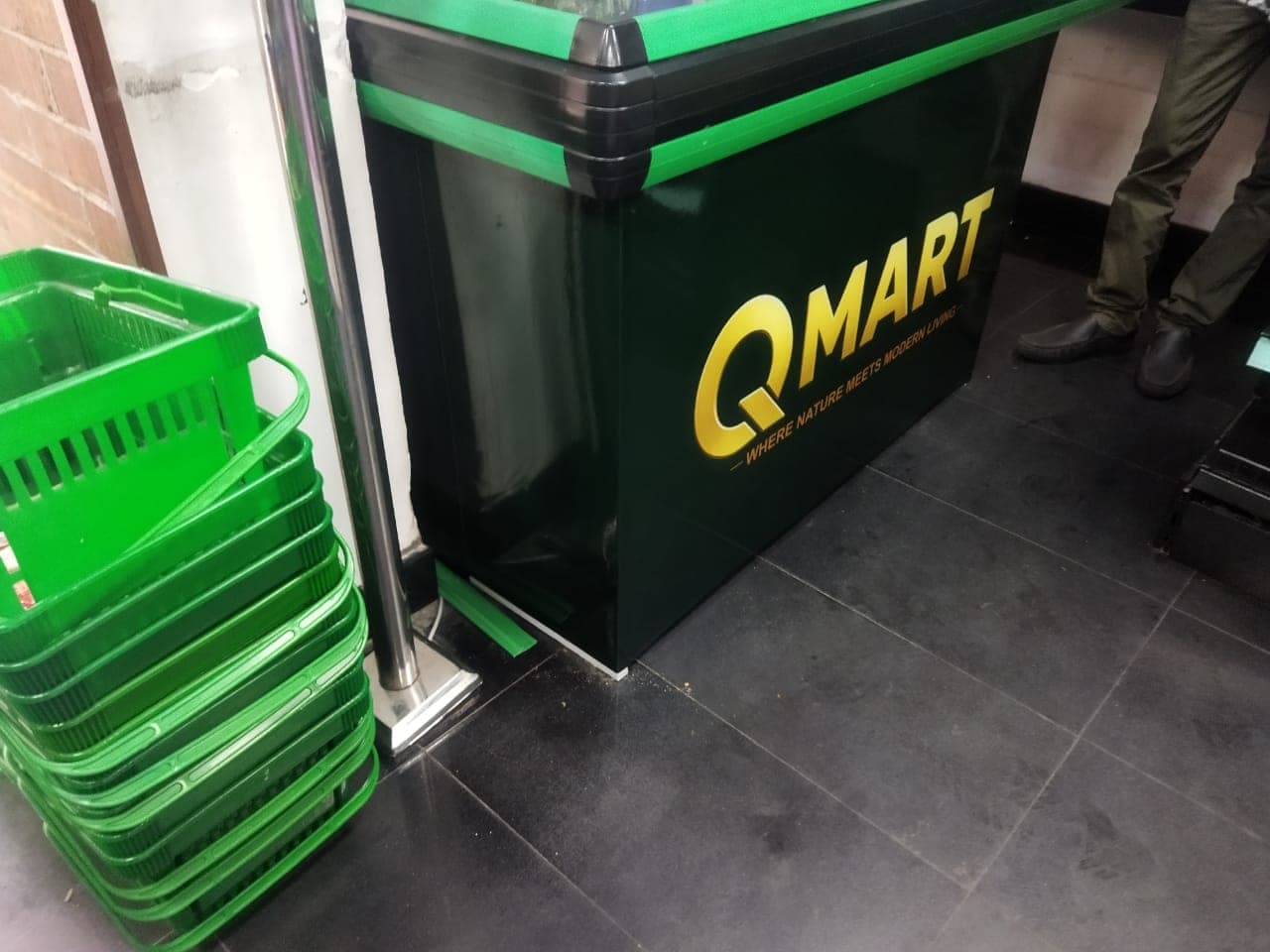 QMart branded green freezer chest beside shopping baskets