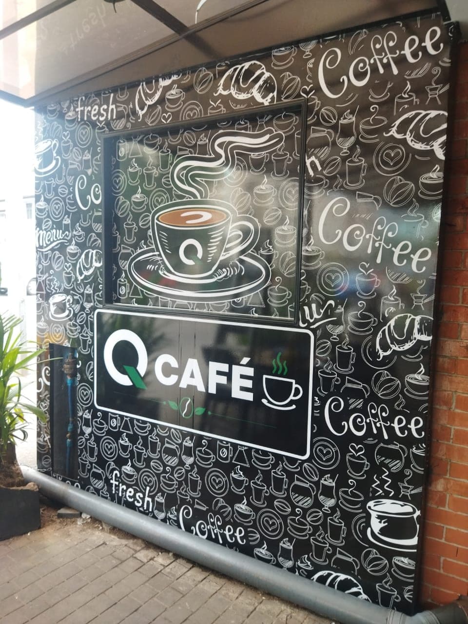 Q Café illuminated lightbox on a chalk-art coffee feature wall