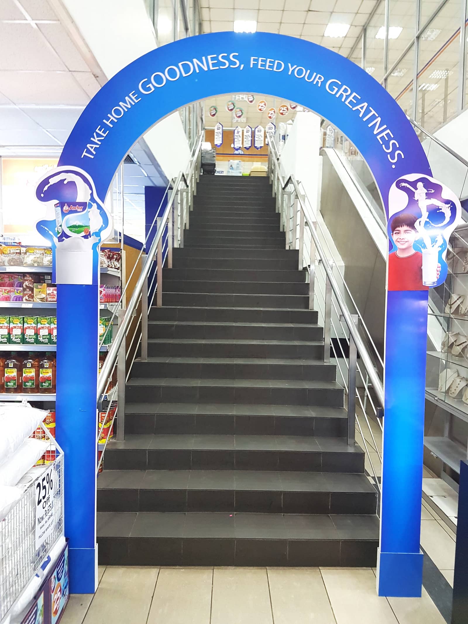 Branded blue archway over a supermarket staircase between aisles